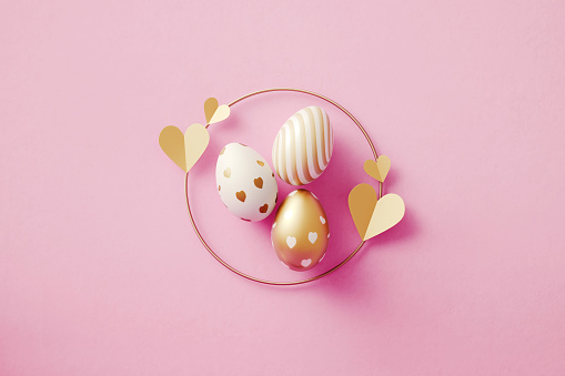 Gold painted Easter eggs on pink background. Horizontal composition with copy space. Easter concept.