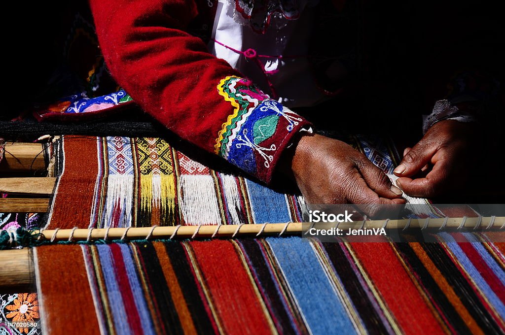 Andean Weaver in Sacred Valley, Cusco, Peru Photo taken of an Andean weavr at work in the Sacred Valley, outside of Cusco.  In Peru this ancient craft is being preserved by government officials and historians who are working to ensure this great craft is kept alive.  She is weaving a tapestry by hand. Textile Stock Photo