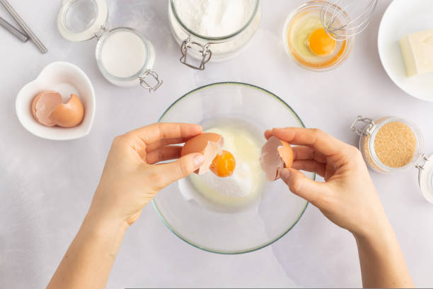 istock Various baking ingredients - flour, eggs, sugar, butter and kitchen utensils on grey background. Woman hands 1470206082