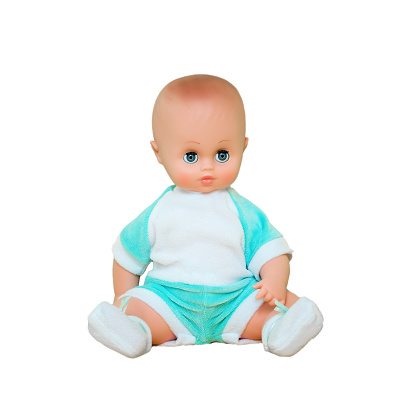 Retro plastic baby doll wearing clothing isolated on white background. Children vintage manufactory dolly toy seated on white place.