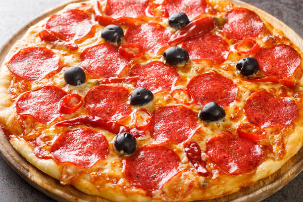 italienische pizza diavola mit scharfer salami und chilis nahaufnahme auf einem holzbrett. horizontal - devil chili stock-fotos und bilder