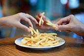 Closeup Of Hands Taking French Fries From The Plate