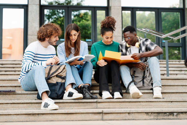 istock Young students sitting on University stairs. College friends studying together after class 1470209715