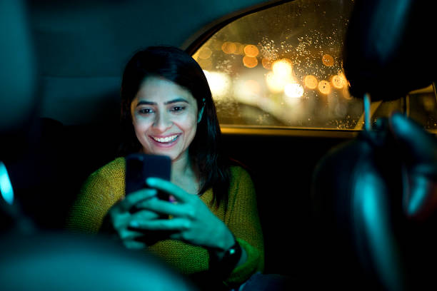 mujer usando el teléfono en el coche por la noche - working smiling equipment car fotografías e imágenes de stock