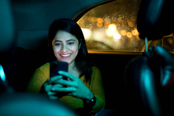 woman using phone in car at night - car equipment smiling working imagens e fotografias de stock
