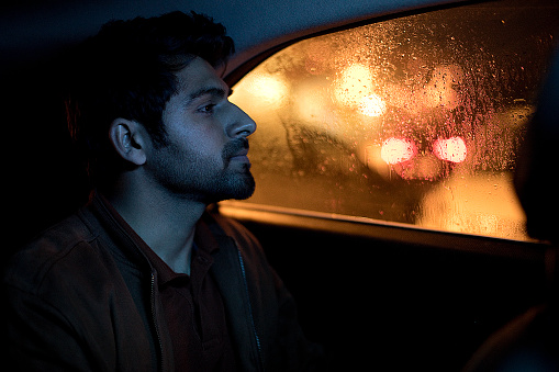 Young man enjoying night ride while sitting on car