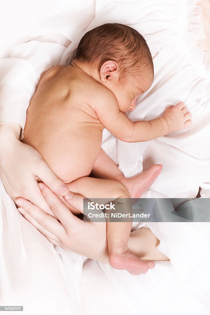 Adult hands cradling naked newborn baby Newborn sleeping child in the hands of mother Baby - Human Age Stock Photo
