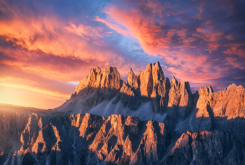 Rocky mountains at amazing colorful sunset in summer in Dolomites, Italy. Mountain ridges and beautiful sky with pink, red and ornage clouds and sunlight in spring. Landscape with rocks, mountain peak