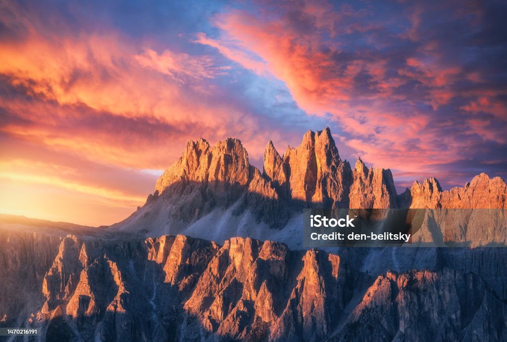 Rocky mountains at amazing colorful sunset in summer in Dolomites, Italy. Mountain ridges and beautiful sky with pink, red and ornage clouds and sunlight in spring. Landscape with rocks, mountain peak Landscape - Scenery Stock Photo