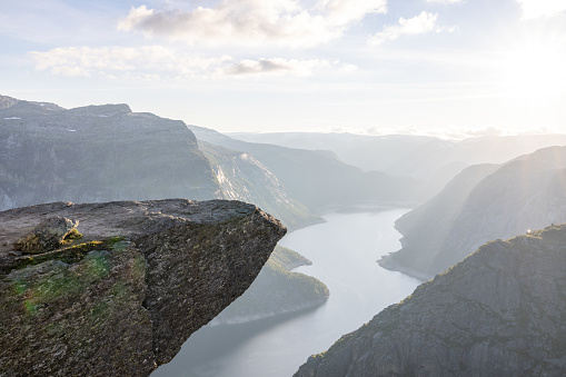 Breathtaking view of Trolltunga rock - most spectacular and famous scenic cliff in Norway. Scenic rocky precipice projecting high above a lake & reachable via a strenuous, 27km hiking trail.