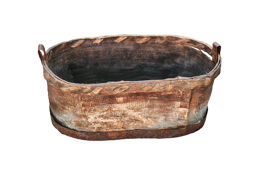 An old trough made from the bark of a tree, isolated on a white background. Vintage washtub woven from wood, with a metal rim at the bottom.