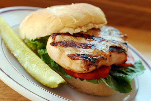 Free-range grilled chicken sandwich Grilled free-range organic chicken breast with lettuce and tomato on a bun. Pickle on the side. dill pickle stock pictures, royalty-free photos & images