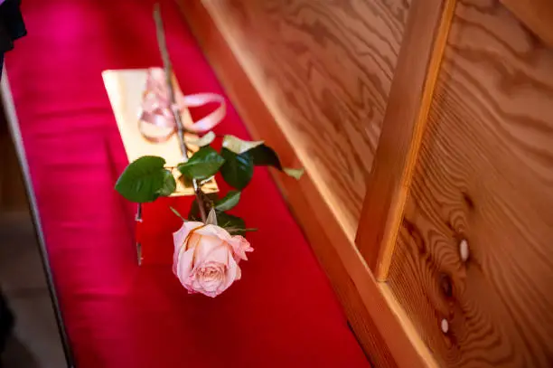 flowers bouquets bouquets and boutonnieres a rose with a ribbon lying on a red wooden bench in the church