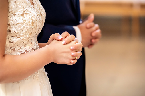 hands, wedding rings and marriage vows hands of the bride and groom during prayer