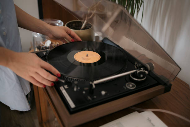 Close-up of a woman playing vinyl record on turntable stock photo