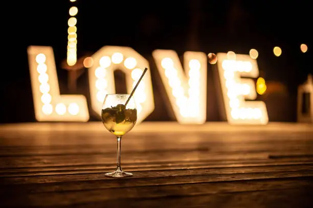 wedding hall interiors and decorations drink with lime and mint in a wine glass against the background of the illuminated inscription love with a shallow depth of field