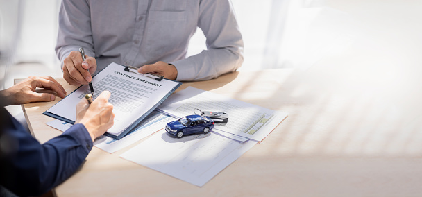 Car Insurance document or lease concept the car broker assisting his customer and explaining the detail of the car contact. Car key Buying or selling signing .