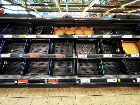 Empty shelves in the supermarket vegetable aisle, during a shortage of tomatoes and cucumbers.