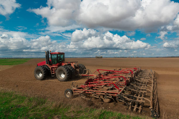 istock Red tractor plows the farm field 1470222595