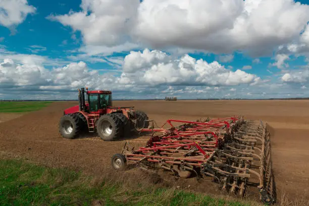 Photo of Red tractor plows the farm field