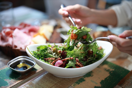 Cropped shot of an asian woman's hand enjoying healthy mixed salad in a restaurant