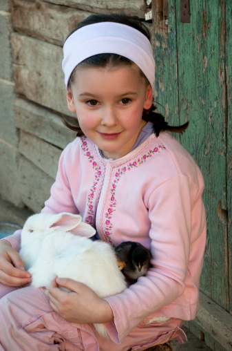 Portrait of little girl with little baby rabbit and little chickens