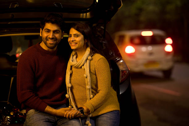 istock Smiling young couple leaning on car at night 1470224231