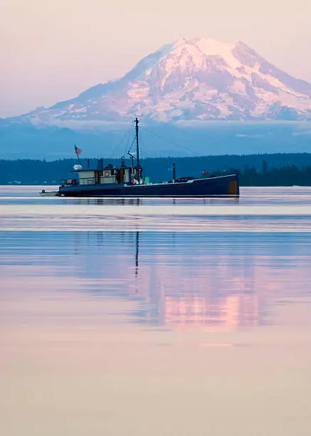 Late afternoon view of boat anchored in Washington State's Puget Sound.  Mt. Rainier and her reflection surround the boat.