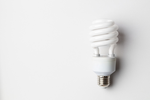 Spiral white light bulb. Energy saving fluorescent light bulb on white background. Green concept.