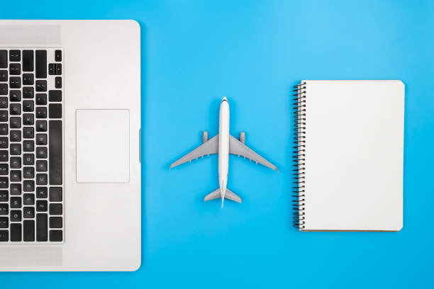 istock Laptop, notepad and airplane miniature on a blue background, flat lay. 1470225785