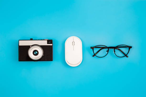 câmera vintage, óculos e mouse de computador em um fundo azul isolado. - antique photo - fotografias e filmes do acervo