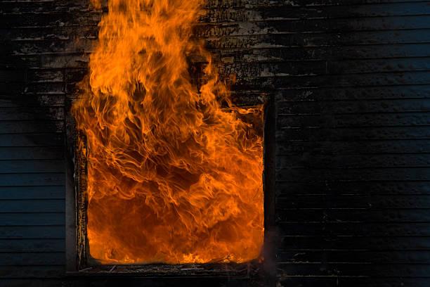 House fire with flames coming out a window stock photo