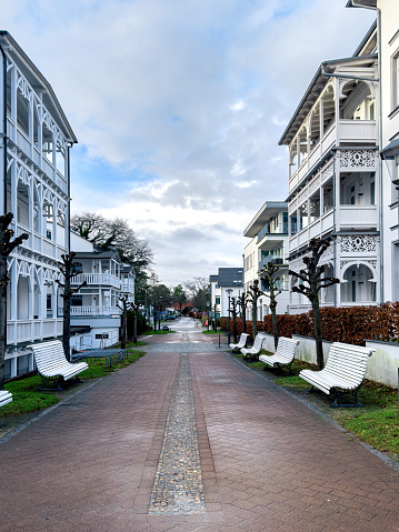 A street with white benches between beautiful white houses, a residential area.