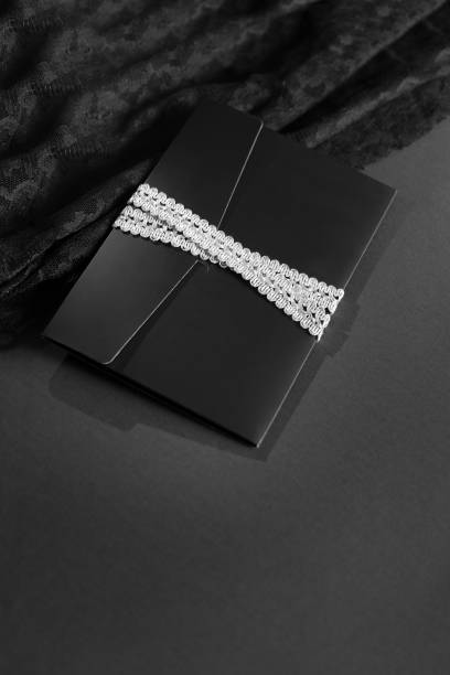istock black envelope mockup, shot from the top on a black background with copy space. Tied with a silver ribbon. 1470229931