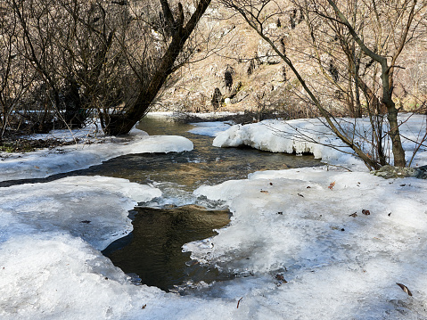 Water flows below, winter background. Streams and rivers melting ice, springtime. Snow melting, flow.