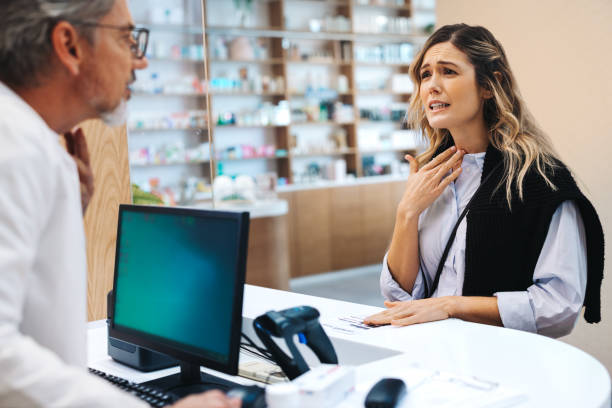 Patient with a cold talking to a pharmacist over the counter stock photo