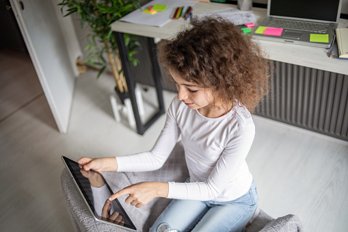 One Caucasian little girl is using a digital tablet at home in her children's room, she is talking online with her friends, watching a video or studying online