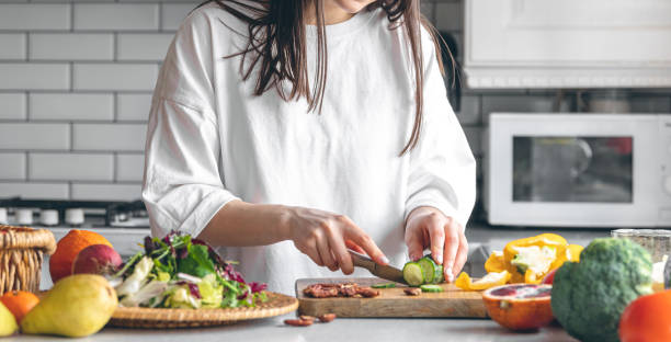 istock A young woman cutting vegetables for salad in the kitchen. 1470237410