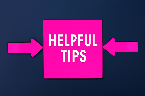 Helpful Tips - inscription of a magenta paper notes and two colorful arrows over a dark blue background. Top view. Business, tips and tricks concept
