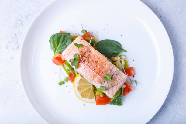 trota (salmone) con verdure, limone e microgreens, cucinata con il metodo confit. un piatto tradizionale francese. foto ravvicinata e selettiva - main course salmon meal course foto e immagini stock