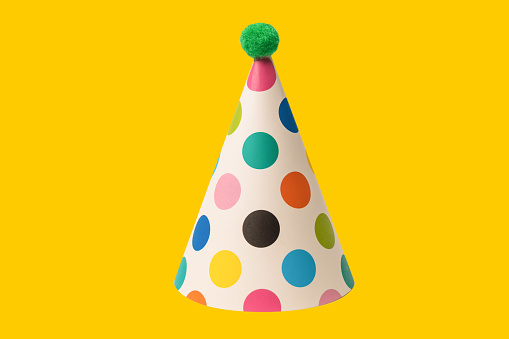 Bright and colorful birthday cap isolated on a yellow background. Holidays cocept.