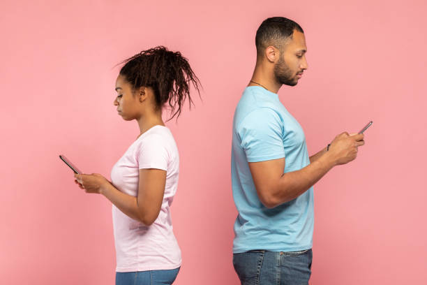 istock Millennial black couple using mobile phones, standing back to back, ignoring each other, playing video games 1470239898
