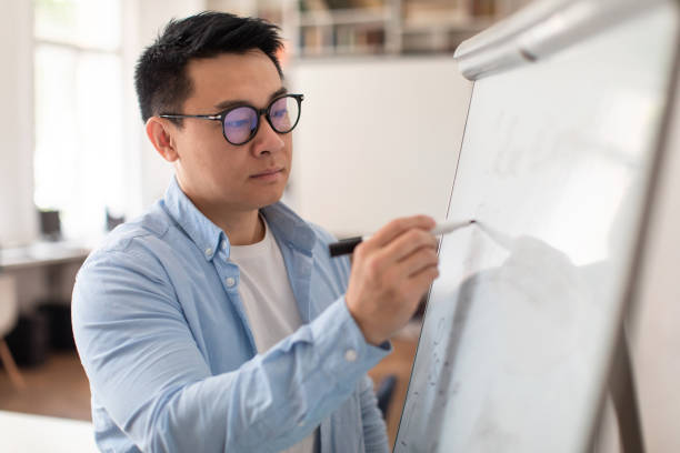 istock Japanese Teacher Man Writing On Blackboard Having Class Indoor 1470239930