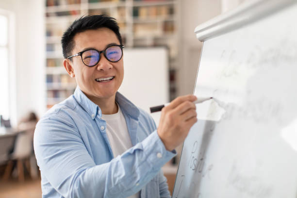 istock Cheerful Chinese Tutor Smiling To Camera Standing In Classroom 1470239968