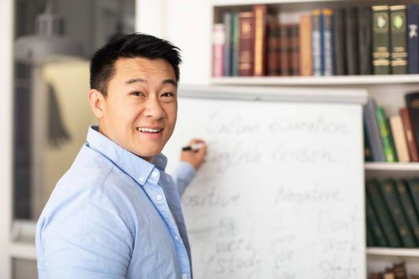 istock Korean Tutor Man Writing On Whiteboard Teaching English In Classroom 1470240108