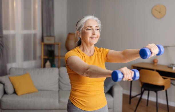 istock Excited senior woman doing domestic training, working out with dumbbells, exercising her biceps at home, free space 1470240782