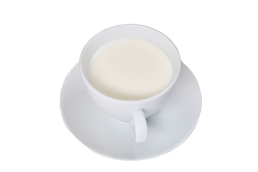 White cup with milk on a saucer, isolated on a white background