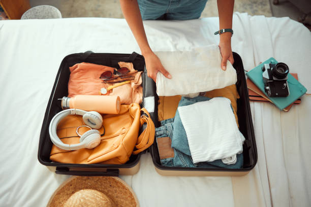 voyage emballage, au-dessus et les mains d’une femme avec des vêtements, des bagages de vacances et se préparer pour l’été international. valise, prête et personne voyageant avec une valise, des vêtements de vacances et un sac d’hôtel - tourist resort audio photos et images de collection