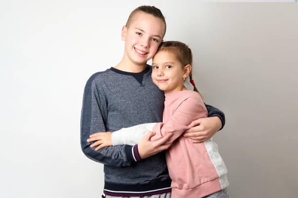Boy and girl hugging each other on white background. Happy young kids. Portrait of brother and sister having fun. Two children's friendship.