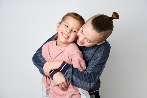 Boy and girl hugging each other on white background. Happy young kids. Portrait of brother and sister having fun. Two children's friendship.
